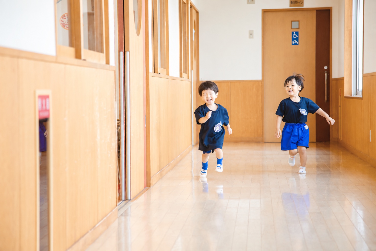 木のぬくもりある廊下を走る園児たち