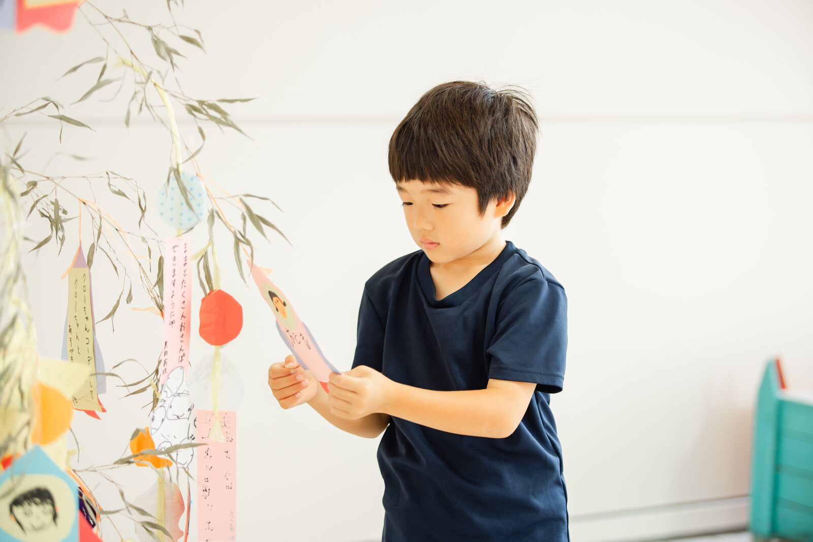 七夕飾りに短冊をつける子ども
